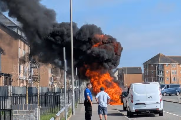Parked car engulfed in flames as thick smoke rises over street